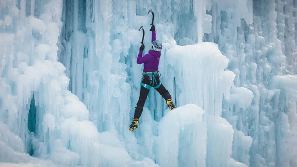 凍った滝の上に氷の登山装置を持つアルピニストの女性 — ストック写真