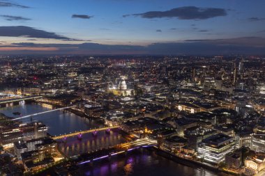 Londra 'da gece hayatı, Thames nehrinin üzerindeki köprüde yoğun trafik... iş bölgesinin yakınında parıldayan gökdelenler, yan manzara....