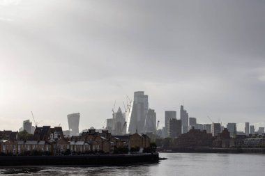Thames Nehri 'nin kıyısındaki Londra rıhtımı konutları ve arka planda modern iş binaları, el kamerasıyla çekilmiş. Geleneksel ve çağdaş mimari konseptin birleşimi.