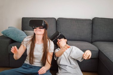 Kafkas ailesi, anne ve oğlu VR kulaklıklar ve sanal gerçeklik deneyiminin tadını çıkaran sanal gerçeklik kontrolörleri.