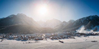 Slovenya 'dan Kranjska Gora kışın karla kaplanırken, arkada Julian Alps ve Triglav Ulusal Parkı bulunuyor. Hava Panoraması