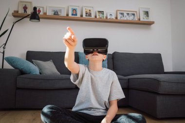 Sanal gerçeklik kulaklığı takıp etrafa bakınarak sanal dünyayı deneyimleyen heyecanlı çocuk.