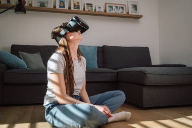 Sanal gerçeklik ekipmanı kullanan genç bir kadın, sanal dünyaya bakmak için VR gözlükleri kullanıyor.