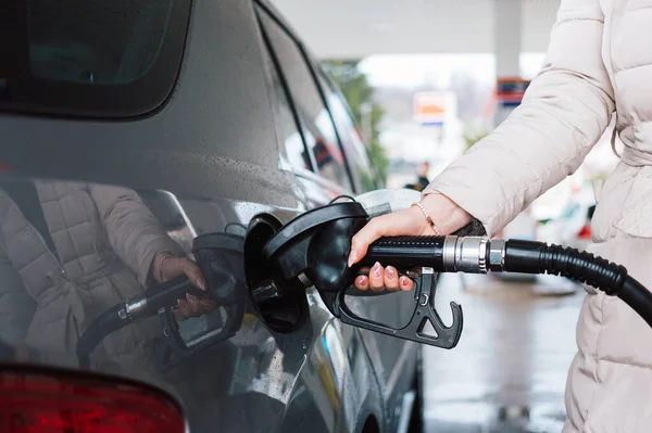 Woman pumping gasoline fuel in car at gas station. Petrol or gasoline price increase concept.