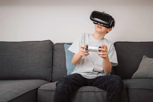 Boy having fun playing simulation games, using virtual reality headset and controller. Children and modern technology concept.