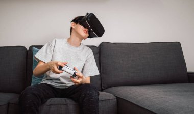 Çocuk sanal gerçeklik kulaklığı ve kontrol cihazı kullanarak simülasyon oyunları oynayarak eğleniyor. Çocuklar ve modern teknoloji kavramı.