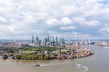 London, UK - September 11 2022 - Business district of London, skyscraper-packed peninsula Canary Wharf, with parks and river Thames nearby, aerial view.