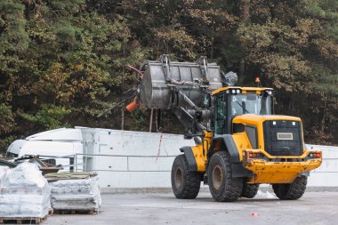 Waste loading operation, loader dumping trash in a truck on a site for the disposal of waste materials