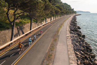 Father, mother, and their two children riding bicycles, enjoying a beautiful summer day, drone shot. Active family vacation concept.