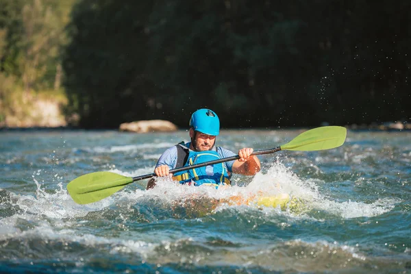 stock image Caucasian man skillfully steering kayak in the river, crossing over whitewater rapids