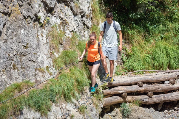 stock image Young active recreational day hikers, woman and man crossing extreme hike trail over rocky slope