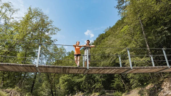 Pareja Cariñosa Excursionistas Recreativos Cruzando Puente Colgante Sobre Lecho Rocoso —  Fotos de Stock
