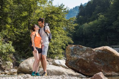Bir çift genç yürüyüşçü, bir kadın ve bir erkek güzel doğa manzarasının tadını çıkarıyorlar, bir dağ taşkınının selfie fotoğraflarını çekiyorlar.