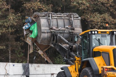 Waste loading operation, loader dumping trash in a truck on a site for the disposal of waste materials