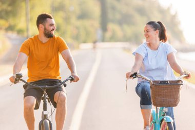Sahil bisikletleriyle gezmekten zevk alan çift deniz kenarında harika bir yolda pedal çeviriyor.