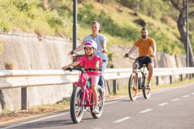 Mother, father and girl child having fun on vacation cycling near the sea. Family coastal bike ride.