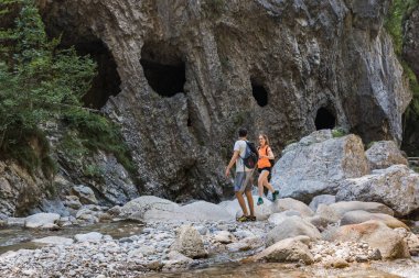 Dağ nehrini geçerken kayalıklarda yürüyen bir çift vadide yürüyüş yapıyor. Seyahat ve macera yaşam tarzı konsepti.