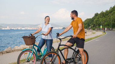 Sahil bisikletleriyle gezmekten zevk alan çift deniz kenarında harika bir yolda pedal çeviriyor.