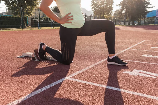 stock image Young woman training for run race start on a stadium track outside