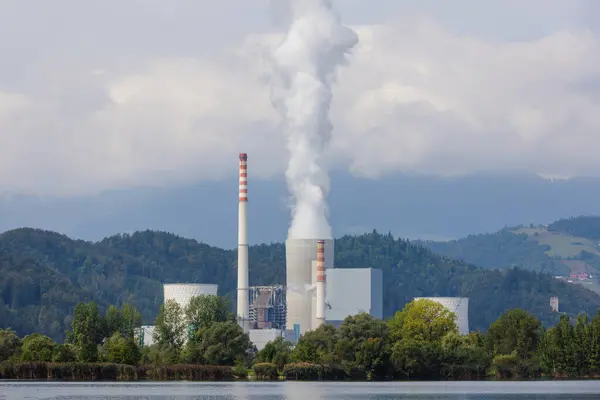 stock image Smoking chimney at thermal power plant near lake and green nature.