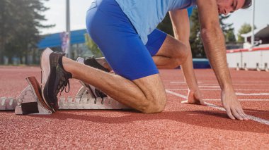 Koşu için antrenman yapan genç adam dışarıda bir stadyum pistinde başlıyor.