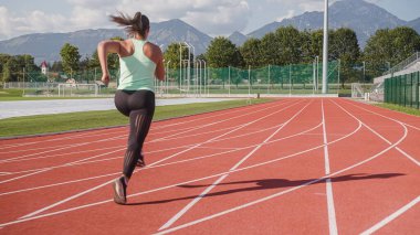 Atlet kadın atletizm pistinde koşmaya başlıyor. Üç sayılık sprint başlangıç pozisyonundan.