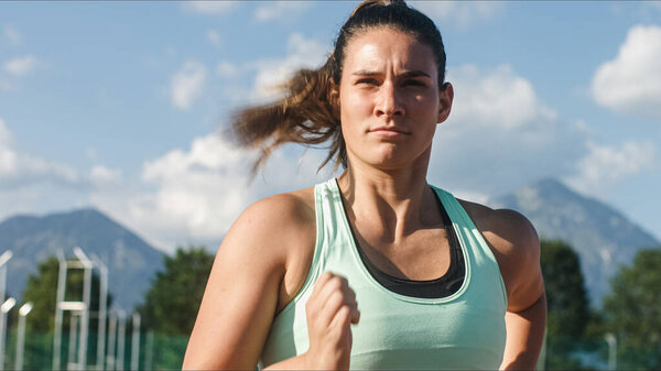 Молодая, сильная, решительная кавказская спортсменка в спринте стартовая позиция в четвертой полосе на беговой дорожке