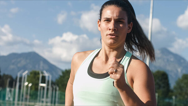 Сосредоточена на сильной кавказской молодой бегунье во время гоночной тренировки на легкоатлетическом треке, средний выстрел.