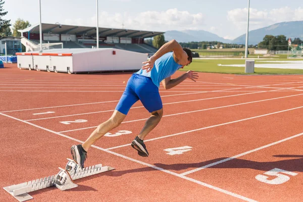 stock image Young man training for run race start on a stadium track outside