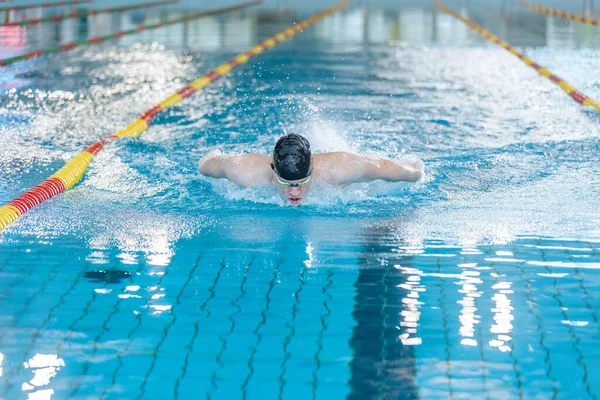 stock image Front view of a female swimmer swimming butterfly style, a stroke performing in a competitive swimming. Success, power, and strength concept.