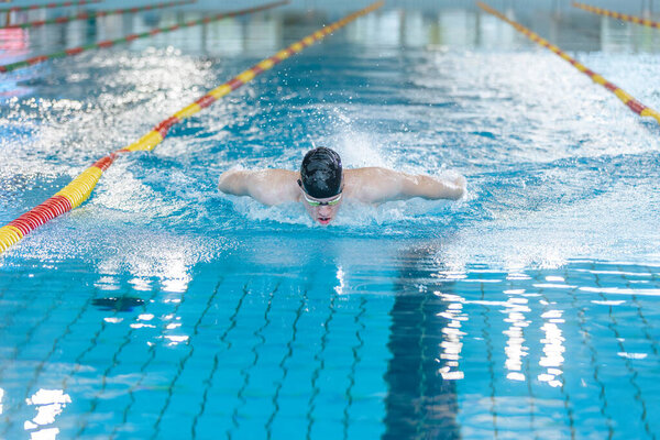 Front view of a female swimmer swimming butterfly style, a stroke performing in a competitive swimming. Success, power, and strength concept.