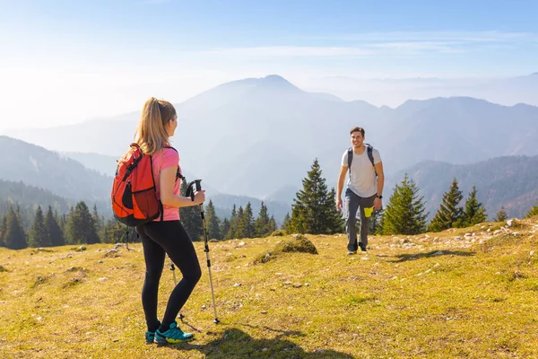 Couple hiking on a clear sunny day, enjoying beautiful mountain nature in autumn. Sport, recreation, and healthy lifestyles concepts.