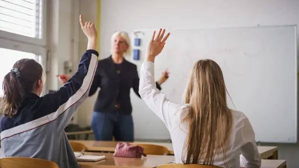 Schülerin Hebt Die Hand Und Beantwortet Eine Fröhlich Lächelnde Lehrerfrage Stockfoto