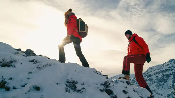 Active couple hiking on extreme terrain in the snowy mountains in winter