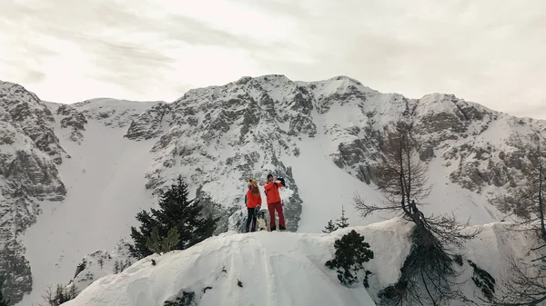 Hikers celebrate the achievement of reaching the top of the mountain in winter, aerial view