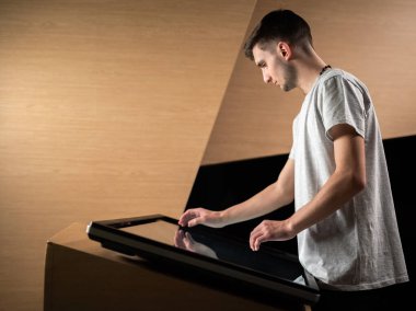 Genç adam dokunmatik ekranın önünde duruyor ve havada farklı el hareketleri yapıyor. Grafik ögesi, boşluk konseptini kopyala.