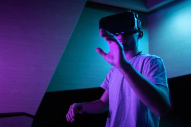 Genç adam dijital dünyada hareket takip teknolojisiyle sanal gerçeklik kulaklığı kullanarak havada el hareketi yapıyor..