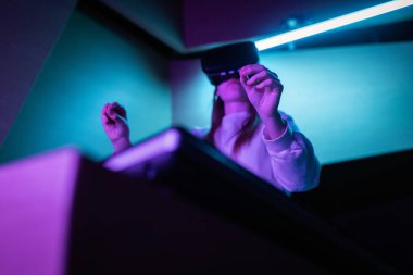 Sanal gerçeklik kulaklığı takmış bir kız dokunmatik ekranın önünde duruyor ve havada el hareketi yapıyor. El izleme konsepti.