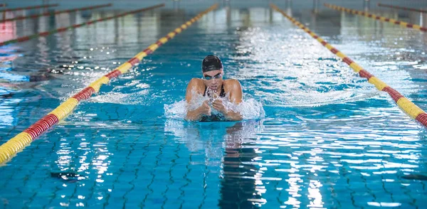 Sportswoman, a professional swimmer using breaststroke drills during a swim training session to improve time and technique