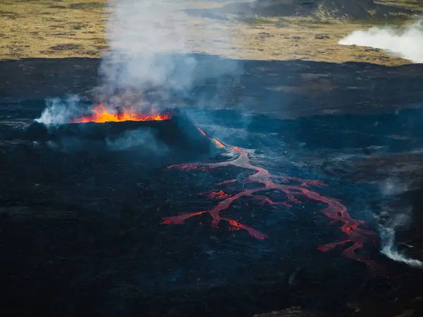 stock image Erupting volcano, red hot boiling lava pouring out of crater into the devastated surrounding area, drone shot. Earth, nature, and power concepts.