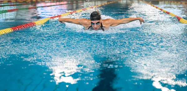 Front view of a female swimmer swimming butterfly style, a stroke performing in a competitive swimming. Success, power, and strength concept.