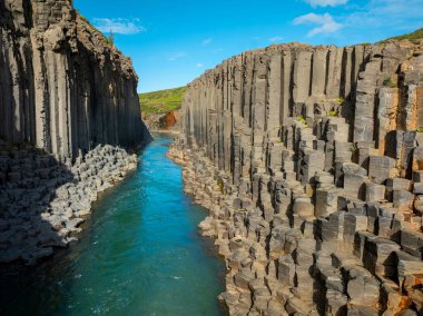 Muhteşem bazalt kolonlardan oluşan kanyon, Kuzey Doğu İzlanda 'da parlak turkuaz nehri olan yüksek uçurum, havadan çekim. Studlagil, doğa güzelliği kavramı..