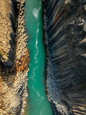 Muhteşem bazalt kolonlardan oluşan kanyon, Kuzey Doğu İzlanda 'da parlak turkuaz nehri olan yüksek uçurum, havadan çekim. Studlagil, doğa güzelliği kavramı..