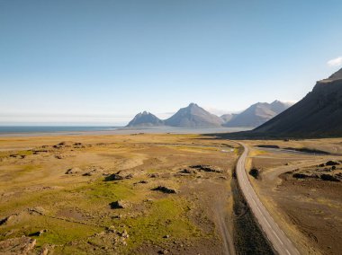 İnanılmaz İzlanda fiyordunun göz kamaştırıcı panoramik görüntüsü, uzakta dağlar, ünlü çevre yolu boyunca, havadan çekim. Seyahat yeri ve doğal cazibe kavramları.