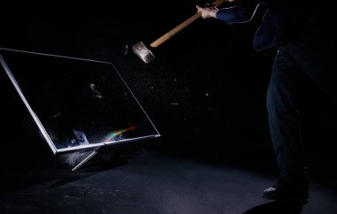 Adam büyük bir düz ekrana balyozla vuruyor, siyah arka planda izole edilmiş, yavaş çekimde kilitlenmiş. Teknoloji, insanlar, fiziksel ve zihinsel sağlık kavramları.