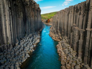 Muhteşem bazalt kolonlardan oluşan kanyon, Kuzey Doğu İzlanda 'da parlak turkuaz nehri olan yüksek uçurum, havadan çekim. Studlagil, doğa güzelliği kavramı..
