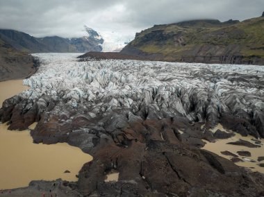İzlanda 'da bulutlu bir günde Svinafellsjokull buzulu, dağlarla çevrili eşsiz buz oluşumları, ve bir buzul gölü, hava manzarası. Doğa ve küresel ısınma kavramları.