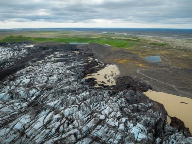 İzlanda 'da bulutlu bir günde Svinafellsjokull buzulu, dağlarla çevrili eşsiz buz oluşumları, ve bir buzul gölü, hava manzarası. Doğa ve küresel ısınma kavramları.