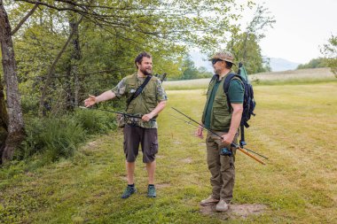 Nehir kıyısında kıdemli ve genç balıkçılar balık tutarken ve konuşurken eğleniyorlar. Doğada keyif ve eğlence kavramları.