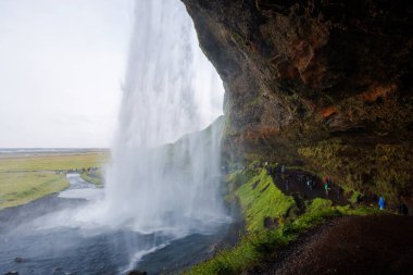 Seljalandsfoss, İzlanda 'da ünlü ve benzersiz bir şelale ziyaretçileri şelalenin arkasında küçük bir mağaraya yürüyor. Trip konsepti.